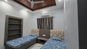 een slaapkamer met twee bedden en een plafondventilator bij Deoghar BnB Homestay in Deoghar