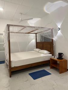 1 dormitorio con cama con dosel y mesa en Villa 95 Hiriketiya, en Dikwella