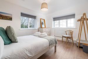 a white bedroom with a bed and a chair at Wallace Hill Cottage - Garsington Studios - Pass the Keys in Stokenchurch