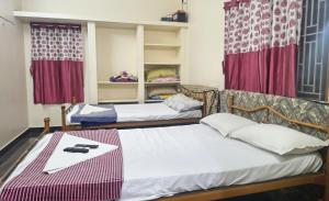 2 Betten in einem Zimmer mit roten Vorhängen in der Unterkunft Aravindh's Chendur HomeStay in Tiruchchendūr