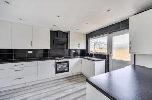 een keuken met witte kasten en een groot raam bij The Escape in Swindon +7 foto's