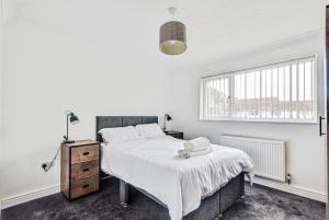 een witte slaapkamer met een groot bed en een raam bij The Escape in Swindon