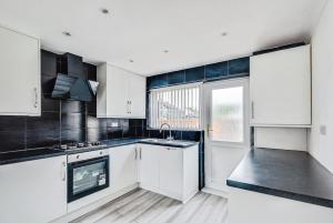 een keuken met witte kasten, een gootsteen en een raam bij The Escape in Swindon