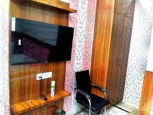 une pièce avec une chaise et une télévision sur un mur dans l'établissement Hotel Golden Time, à Karnal