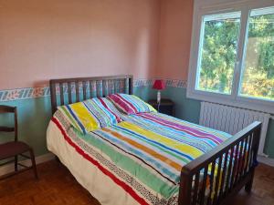 a bedroom with a bed with a colorful striped comforter at Maison BERDOT in Sévignac-Thèze