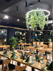 Promocje Amber Park Spa في نيخوجة: مطعم يحتوي على طاولات وكراسي خشبية وثريا