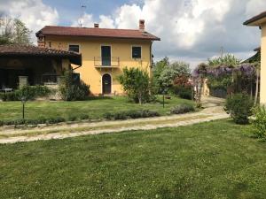 a yellow house with a grass yard and a driveway at Il cotogno in Carrosio