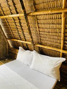 a bed in a thatched room with two pillows at Diapila baybayon Sunset View in El Nido