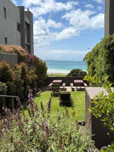 Un jardín con mesas y sillas y el océano al fondo. en Luxury Oceanfront Unit - Cumberland Lorne Resort, en Lorne