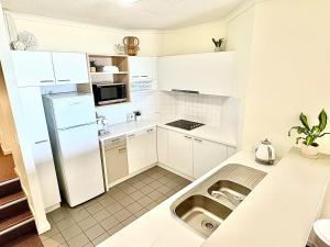 Una cocina blanca con fregadero y refrigerador. en Luxury Oceanfront Unit - Cumberland Lorne Resort, en Lorne