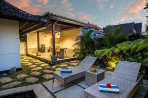 a patio with two chairs and a table in a house at Wardana Ubud Villa I in Ubud