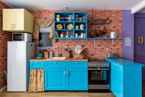 eine Küche mit blauen Schränken und einer Ziegelwand in der Unterkunft Appartement immersif - ambiance série TV in Saint-Étienne + 2 Fotos