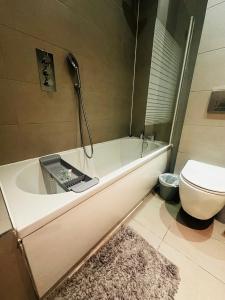 a bathroom with a bath tub and a toilet at Marlowes Flat 3 in Hemel Hempstead +11 photos