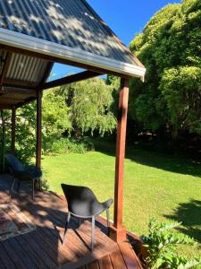 two chairs and a chair sitting on a deck at RIMU CABIN At the Bridge in Motungarara