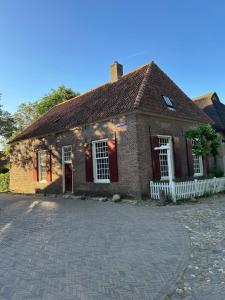 an old brick house with a white fence at Slapen in Bronkhorst in Bronkhorst +5 photos