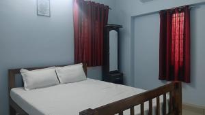1 dormitorio con 1 cama con cortinas rojas en Urban white villa homestay, en Pondicherry