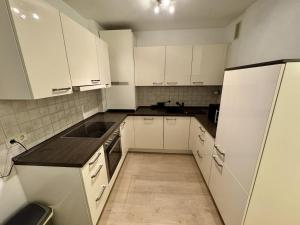 Il comprend une cuisine blanche avec des placards blancs et du parquet. dans l'établissement Apartment with underground parking in Langenfeld, à Langenfeld