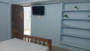 Un dormitorio con una cama y un televisor en una pared. en Urban white villa homestay, en Pondicherry