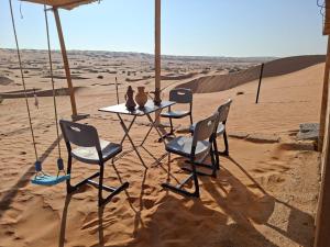 uma mesa e cadeiras na areia no deserto em ESCAPE cAMp2 em Badīyah mais 16 fotografias