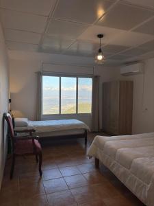 Un dormitorio con dos camas y una silla y una ventana. en Large Vacation Apartment With A Stunning View In Isfiya, Mount Carmel - דירת נופש עם נוף מדהים בעספיא, en ‘Isfiyā 13 fotos más