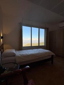 Un dormitorio con una cama y una ventana grande. en Large Vacation Apartment With A Stunning View In Isfiya, Mount Carmel - דירת נופש עם נוף מדהים בעספיא, en ‘Isfiyā