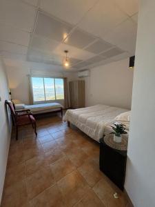 Un dormitorio con una cama y una silla y una ventana. en Large Vacation Apartment With A Stunning View In Isfiya, Mount Carmel - דירת נופש עם נוף מדהים בעספיא, en ‘Isfiyā