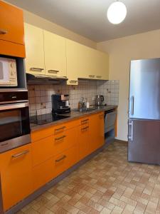 a kitchen with orange cabinets and a stainless steel refrigerator at La ferme de Marin in Marin