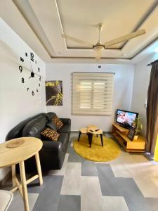 ParakouRésidences Fifamè的客厅配有黑色真皮沙发和时钟