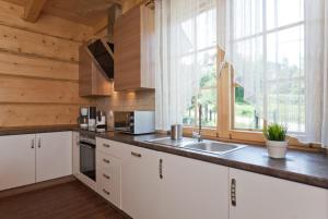 een keuken met witte kasten en een groot raam bij Gorczański Domek - Koninki in Poręba Wielka