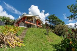 ein Haus auf einem grasbewachsenen Hügel in der Unterkunft Villa Familiar 3BR Vistas al Valle & Naturaleza in Turrialba