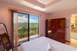 ein Schlafzimmer mit einem Bett und einem großen Fenster in der Unterkunft Villa Familiar 3BR Vistas al Valle & Naturaleza in Turrialba