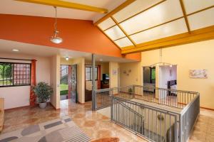 eine offene Lobby mit orangefarbenen Wänden und einem Balkon in der Unterkunft Villa Familiar 3BR Vistas al Valle & Naturaleza in Turrialba