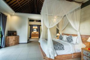 a bedroom with a bed with a mosquito net at Wardana Ubud Villa I in Ubud