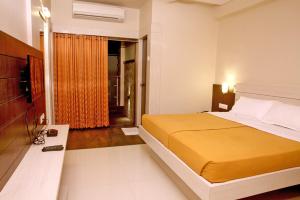 um quarto com uma grande cama amarela e uma janela em Hotel Sham Suman, Kolhapur- Opposite To Mahalaxmi Temple em Kolhapur