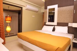 um quarto com uma cama amarela e uma janela em Hotel Sham Suman, Kolhapur- Opposite To Mahalaxmi Temple em Kolhapur