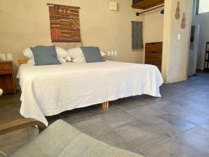 a bedroom with a large white bed with blue pillows at Entire Casita Ocean Breeze & Forest Calm in Troncones