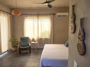 a bedroom with a bed and a chair and a window at Entire Casita Ocean Breeze & Forest Calm in Troncones