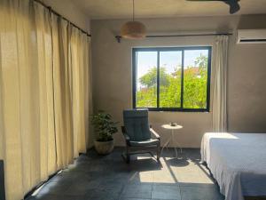 a bedroom with a bed and a chair and a window at Entire Casita Ocean Breeze & Forest Calm in Troncones