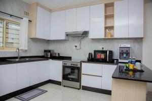 Zanube Apartments في ندولا: مطبخ بخزائن بيضاء وفرن موقد