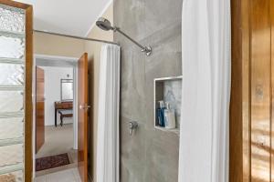 a shower with a white shower curtain in a bathroom at Selwyn Cottage in Burnt Pine +8 photos