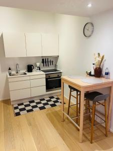a kitchen with white cabinets and a table and a clock at Exclusive Aalborg Harbourfront Apartment with Private Entrance in Aalborg