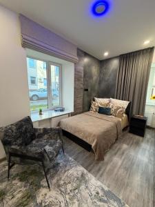a bedroom with a bed and a chair and a window at Koralas in Klaipėda