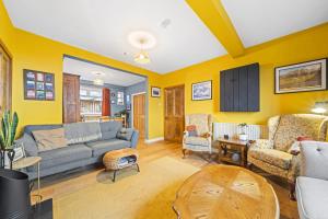 uma sala de estar com paredes amarelas e um sofá azul em Beinn View 3 Bedroom House - Sea View - Ardersier em Ardersier