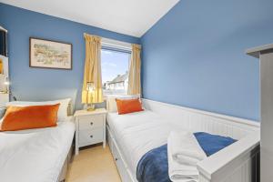 Duas camas num quarto com paredes azuis e uma janela em Beinn View 3 Bedroom House - Sea View - Ardersier em Ardersier