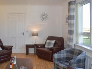 een woonkamer met 2 stoelen en een bank bij Lochboisdale Cottage in Lochboisdale