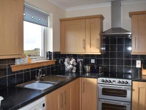 een keuken met een spoelbak en een fornuis bovenste oven bij Lochboisdale Cottage in Lochboisdale +18 foto's