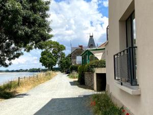 a road next to a building next to a body of water at Maison du pêcheur , située sur les bords de la Loire dans un lieu calme et paisible. in Rochefort-sur-Loire