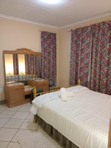 a bedroom with a bed and a mirror and curtains at VSA SELF CATERING accommodation unit 2 in Newcastle +26 photos