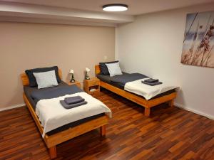zwei Betten in einem Zimmer mit Holzboden in der Unterkunft Gemütliches Apartment in Giengen an der Brenz