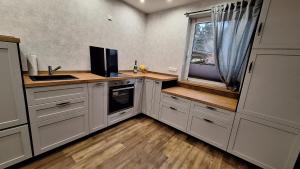 eine Küche mit weißen Schränken und ein Fenster mit einem Waschbecken in der Unterkunft Ferienhaus Burgblick in Blankenburg in Michaelstein